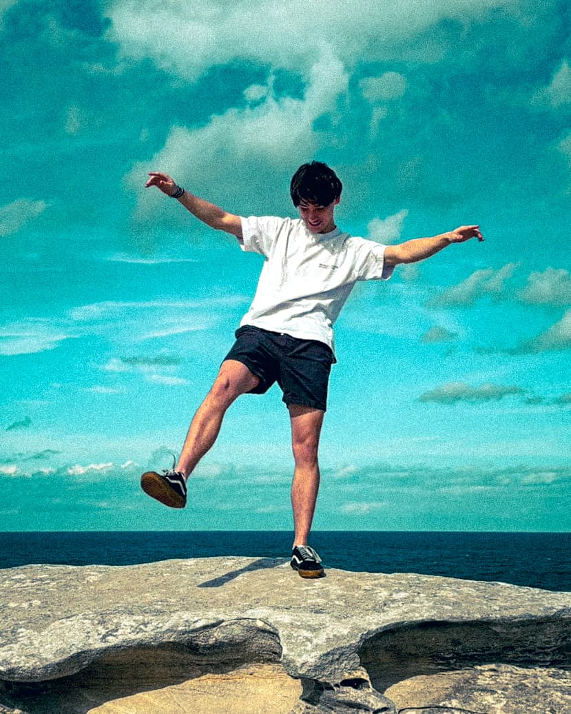 Josh Hatchard balancing on rocks by the ocean